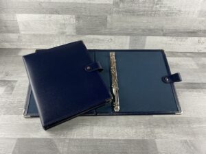 oatlands blue 4 'D' 20 oatlands recycled leather folders. one open showing the 4D 20mm ring mechanism with a navy oatlands ring binder propped on the left hand size closed.