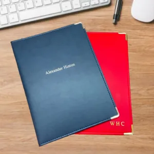 Two document letter folders. one in navy with silver foil blocking on the centre front cover, the other is a red folder with gold blocking on the bottom right hand corner